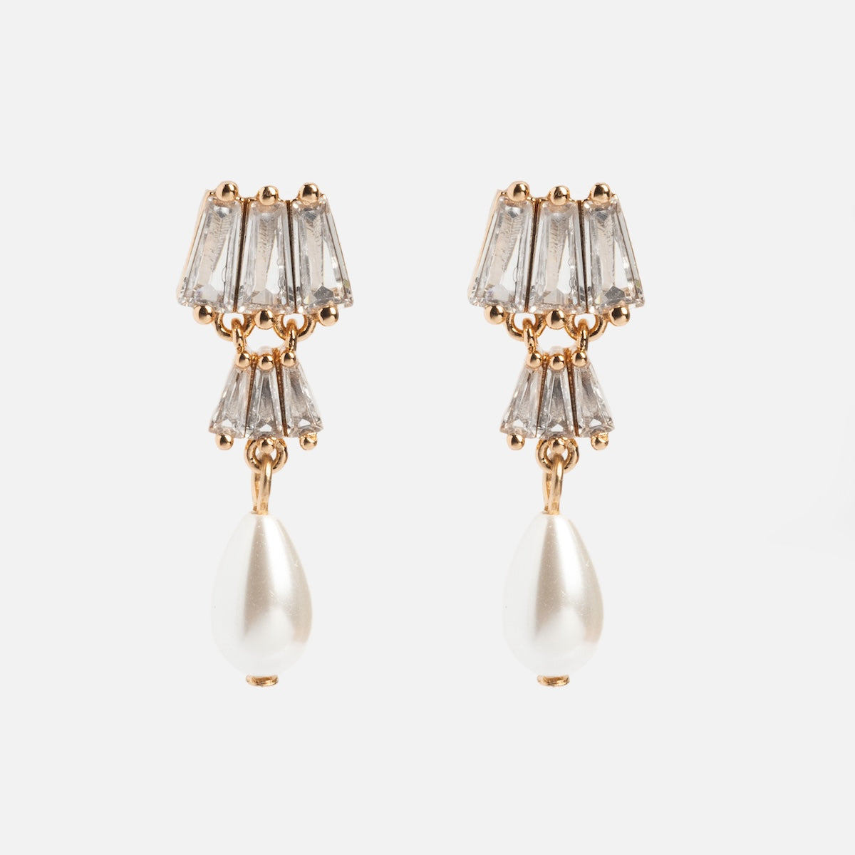 The Rue Drop Earrings feature three clear, trapezoid gemstones stacked above a dangling teardrop-shaped pearl in gold, perfect for fans of elegant Art Deco style.