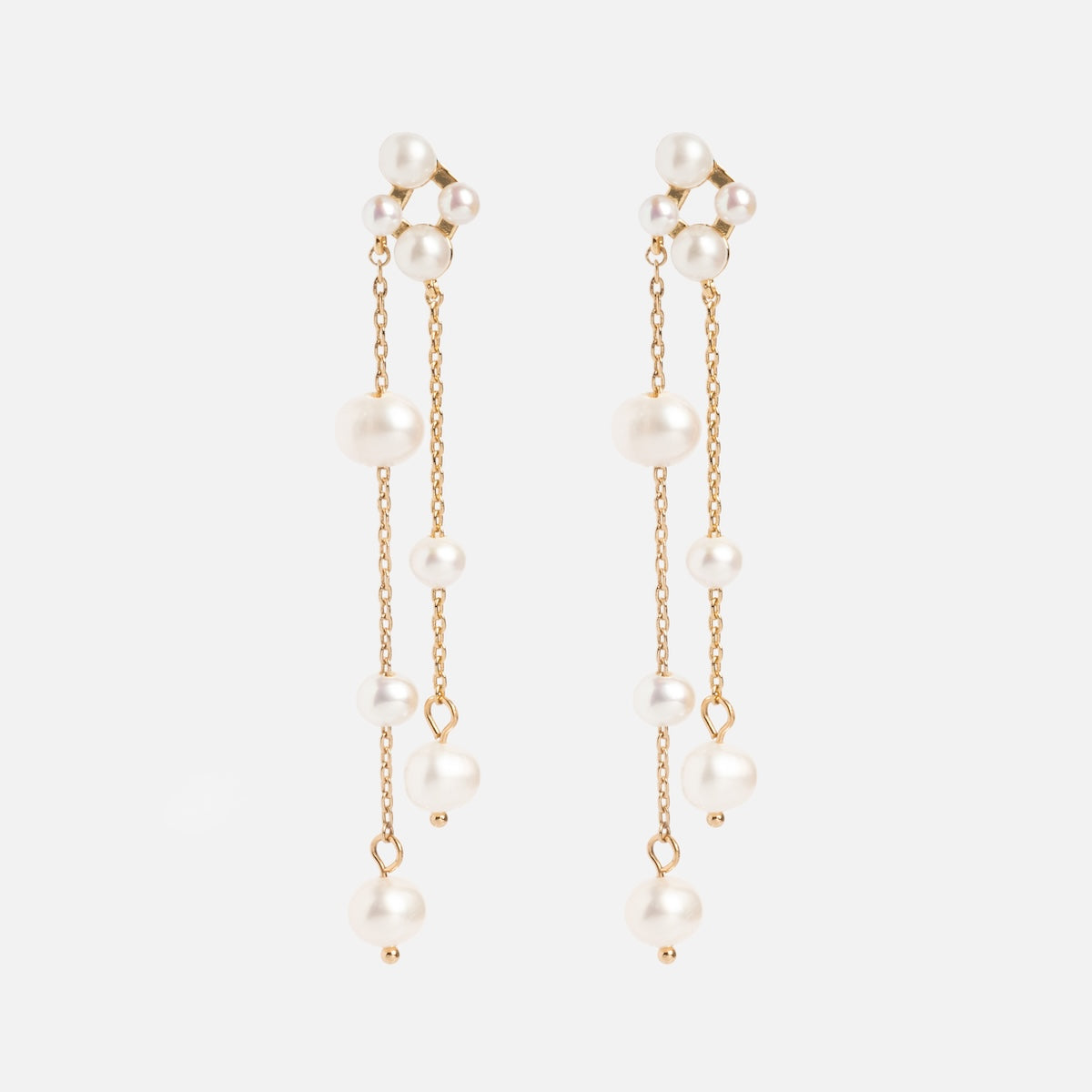 The Felicity Drop Earrings are gold plated with two delicate chains on each, adorned with small and medium freshwater pearls, displayed against a plain white background.