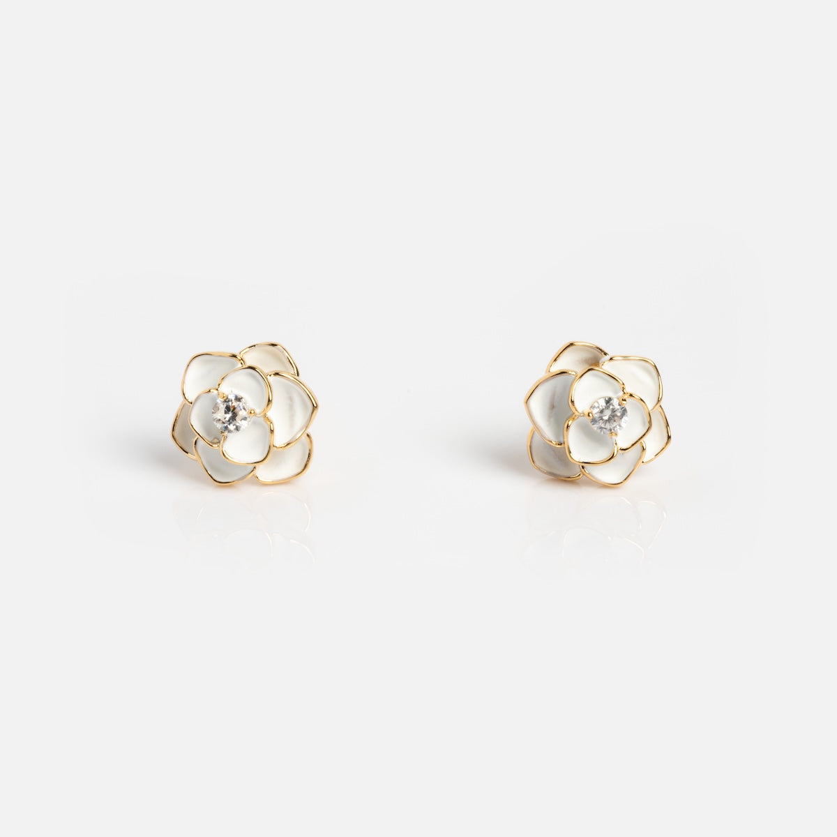 The Sparkling White Rose Studs are enamel earrings shaped like roses with white petals, gold outlines, and a central sparkling gemstone, shown against a plain white background.