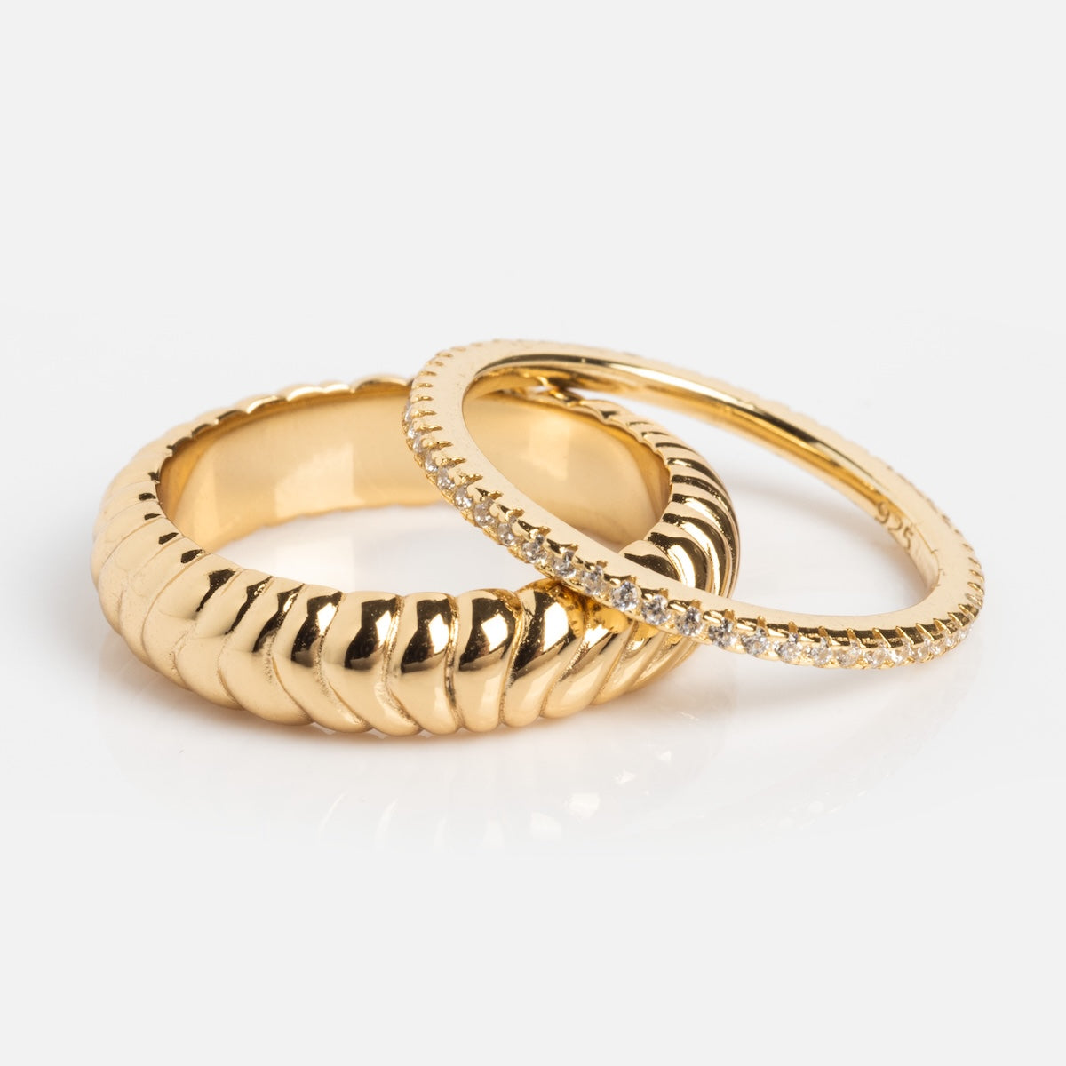 The Reagan Ring Set includes two radiant 14k yellow gold plated rings: one thick, ribbed band and one thin, smooth band with sparkling clear stones.