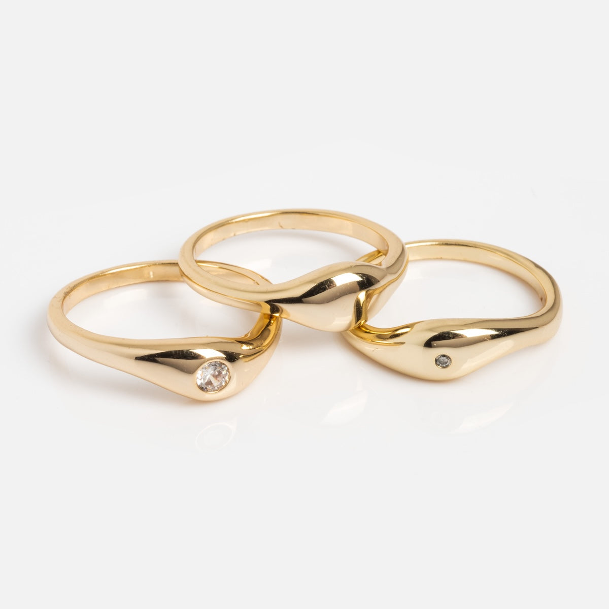 The Delphine Solitaire Ring Set showcases yellow gold rings, including a solitaire and a wavy design, both accented with a sparkling diamond.