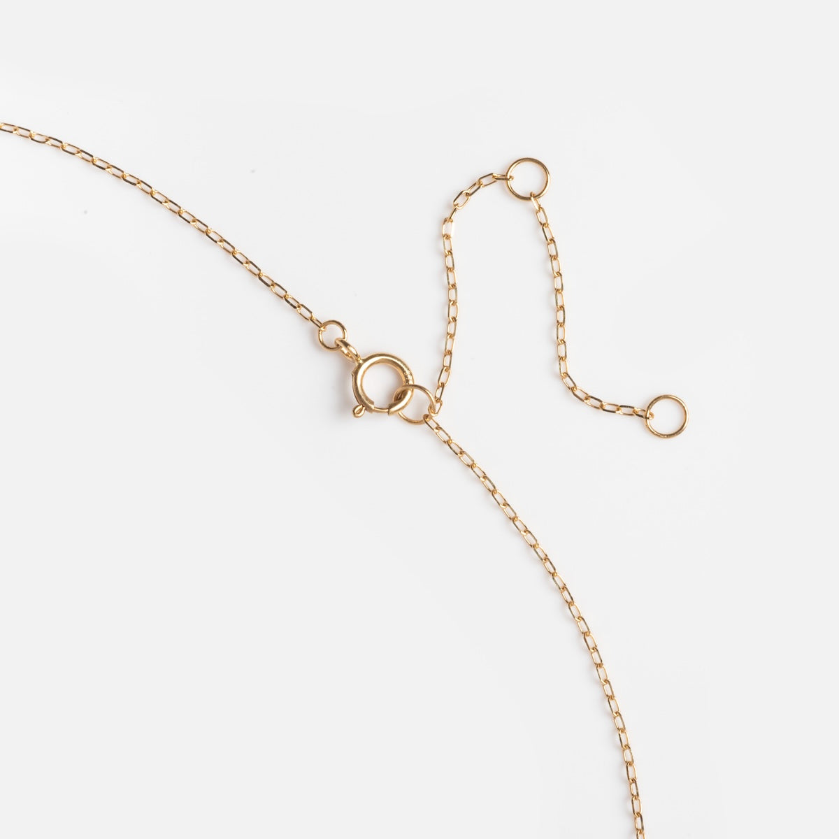 The Solid Gold 2025 August Capsule Vintage Inspired Peridot Drop Necklace features a delicate chain with a spring ring clasp and two small circular links, showcased against a white background.