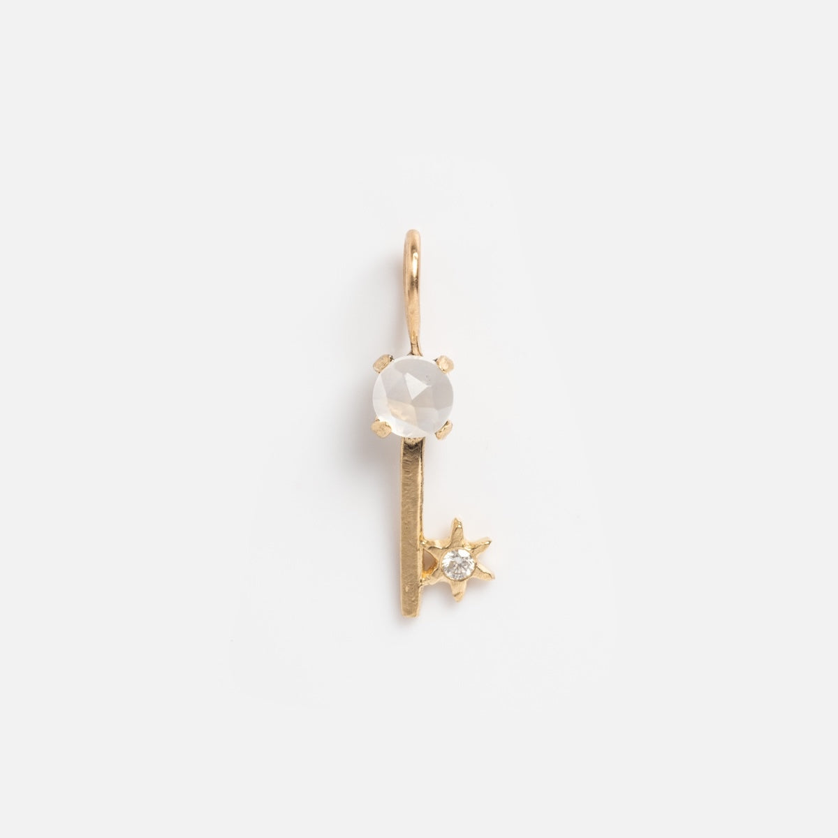 The 14k Solid Gold Tiny Charms by Acanthus features a vertical pendant with a round faceted white gemstone atop and a small star-shaped accent set with a clear stone at the bottom, crafted in solid yellow gold against a white background.