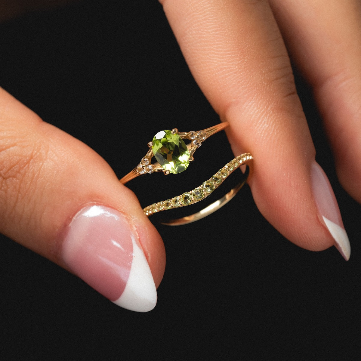 Peridot statement and stacking ring pinched between fingers