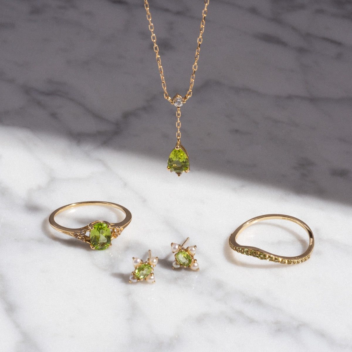 Peridot rings, necklace and earring collection displayed on marble