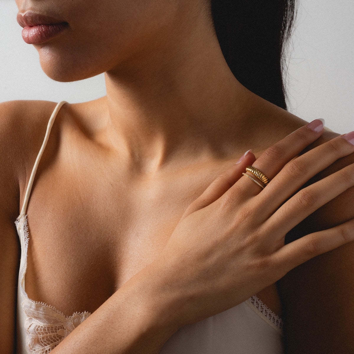 A woman showcases a striking stack of rings, highlighting the Reagan Ring Set in 14k yellow gold plating.