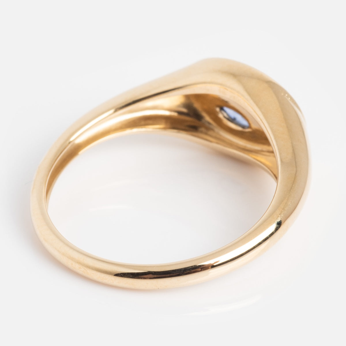 Back of gold ring with a blue gemstone on a white background