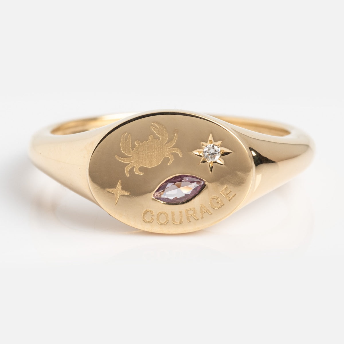 Gold ring with engraved design and gemstones on a light background
