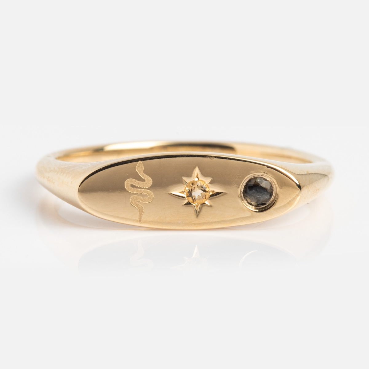 Gold manifestation ring with snake, star and gemstone design on a white background