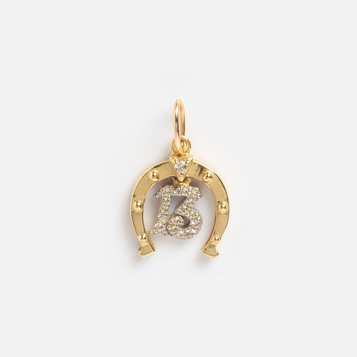 The Solid Gold Lucky Charm features a horseshoe-shaped pendant with a diamond-encrusted number 13 at the center, hanging from a small gold loop, displayed against a plain white background.