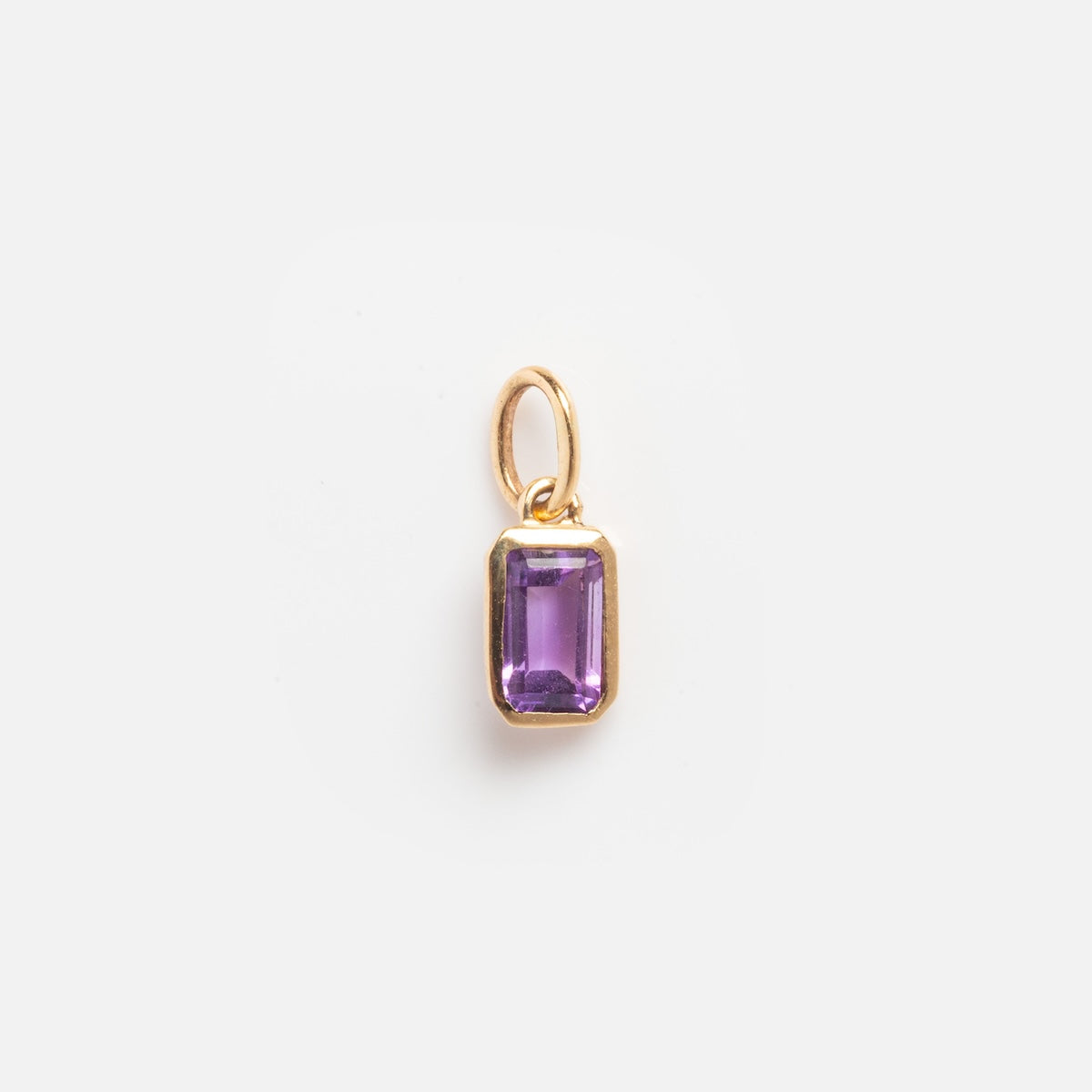 The Solid Gold Birthstone Baguette Charm February Sample features a small rectangular purple gemstone set in a gold frame with a gold loop, shown against a plain white background.