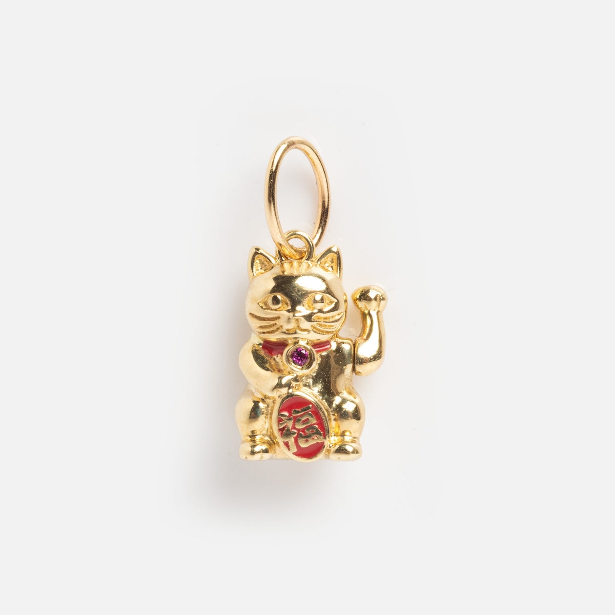 The Solid Gold Lucky Charm features a maneki-neko (Japanese lucky cat) design with a raised paw, red collar, and red stomach detail, attached to a gold loop and displayed on a plain white background.