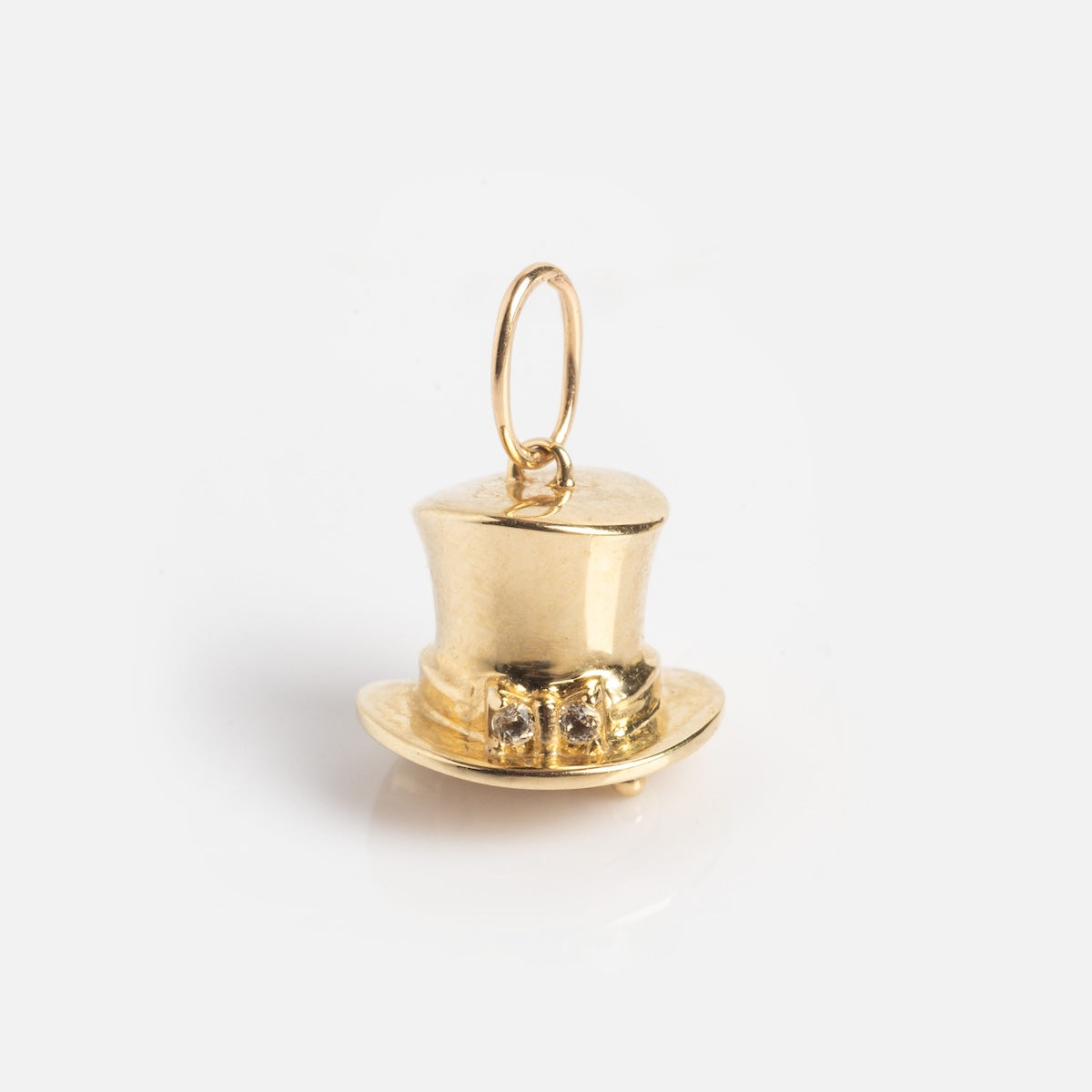 The Solid Gold Lucky Charm is a top hat-shaped pendant with a small attachment loop, decorative detailing, and a shiny finish, shown against a plain white background.