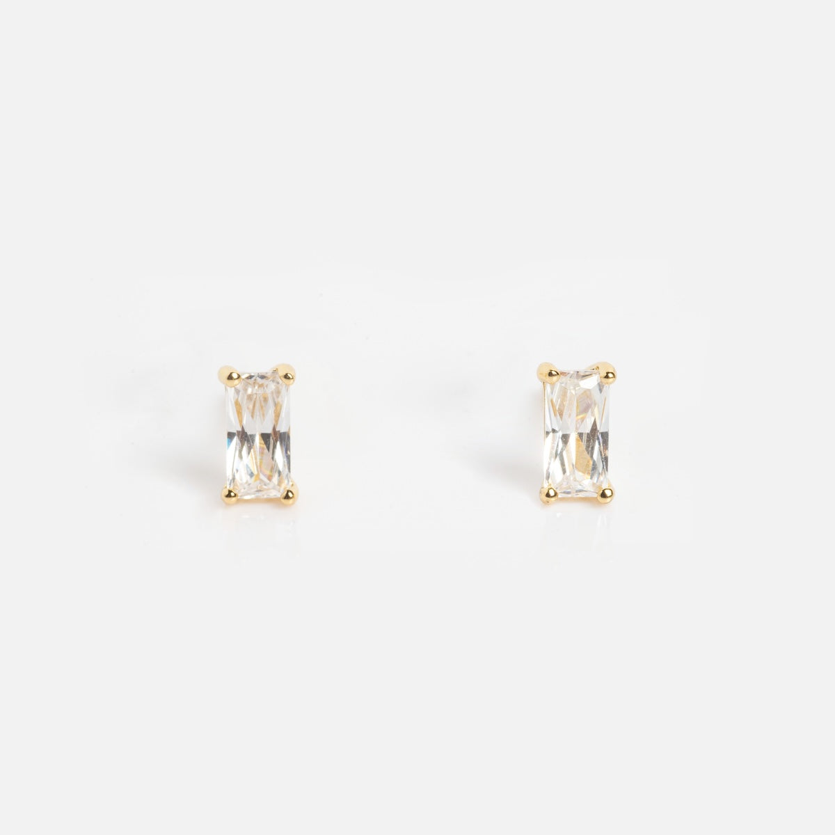 The Birthstone Baguette Studs April Sample features rectangular, clear gemstone studs set in gold prongs and is displayed against a plain white background.
