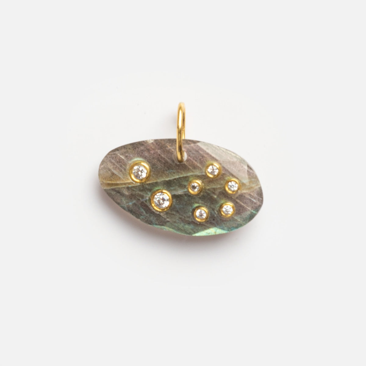 The Labradorite Leo Constellation Charm Sample features an oval iridescent labradorite stone with seven small gemstones in a scattered pattern, set in gold with a top loop for attaching to a chain. Photographed on a plain white background.