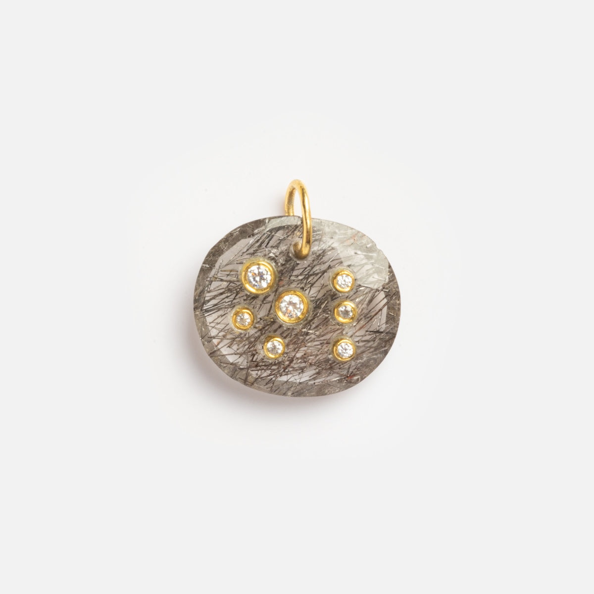 The Black Rutile Scorpio Constellation Charm Sample is a round gray stone pendant with black streaks, seven small clear gemstones arranged in a constellation pattern, and a gold loop for attachment.