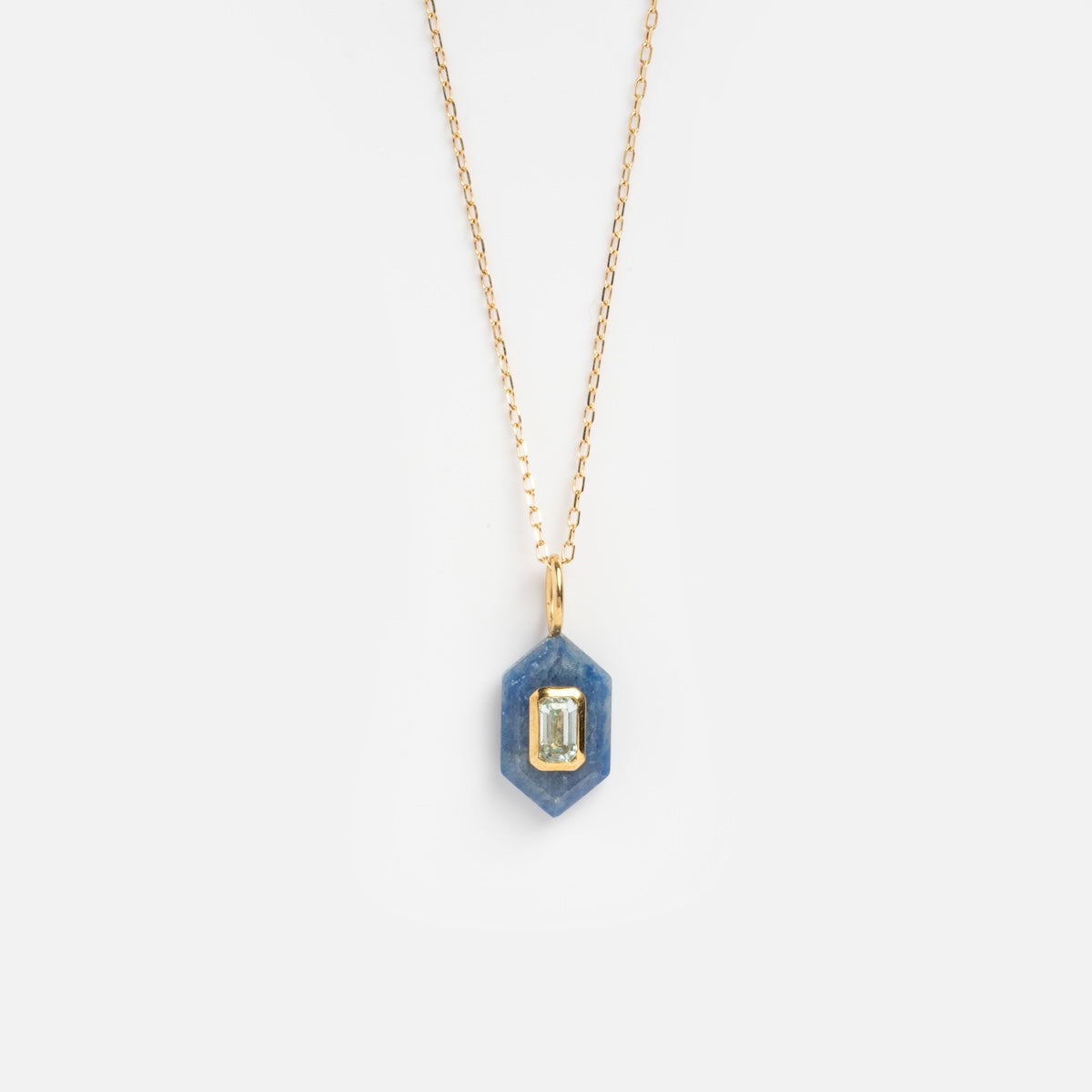 The Solid Gold Large Aura Necklace Blue Sample features a hexagonal blue pendant with an emerald-cut gemstone at the center, shown against a plain white background.