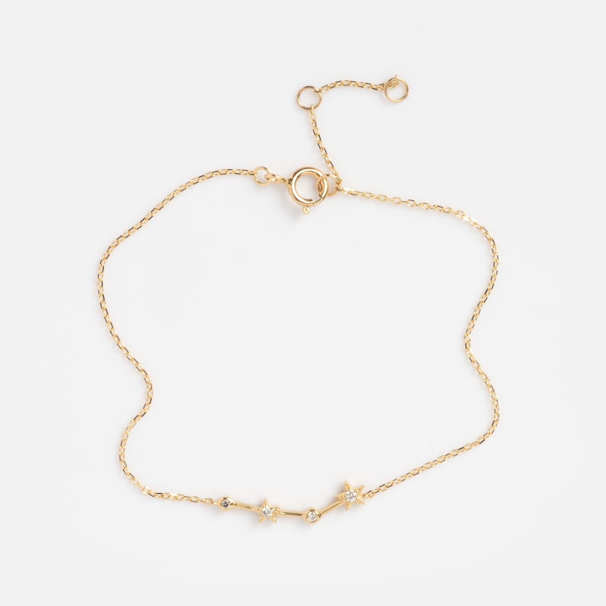 The Solid Gold Zodiac Bracelet Aries Sample features a delicate gold chain with three star-shaped charms, each set with a clear gemstone at the center and finished with an adjustable clasp. Shown on a plain white background.