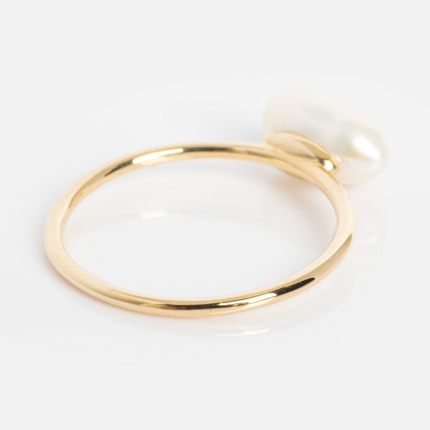 The Solid Gold Organic Pearl Solitaire Ring features a single uniquely shaped white pearl atop a slim gold band, showcased against a white background.