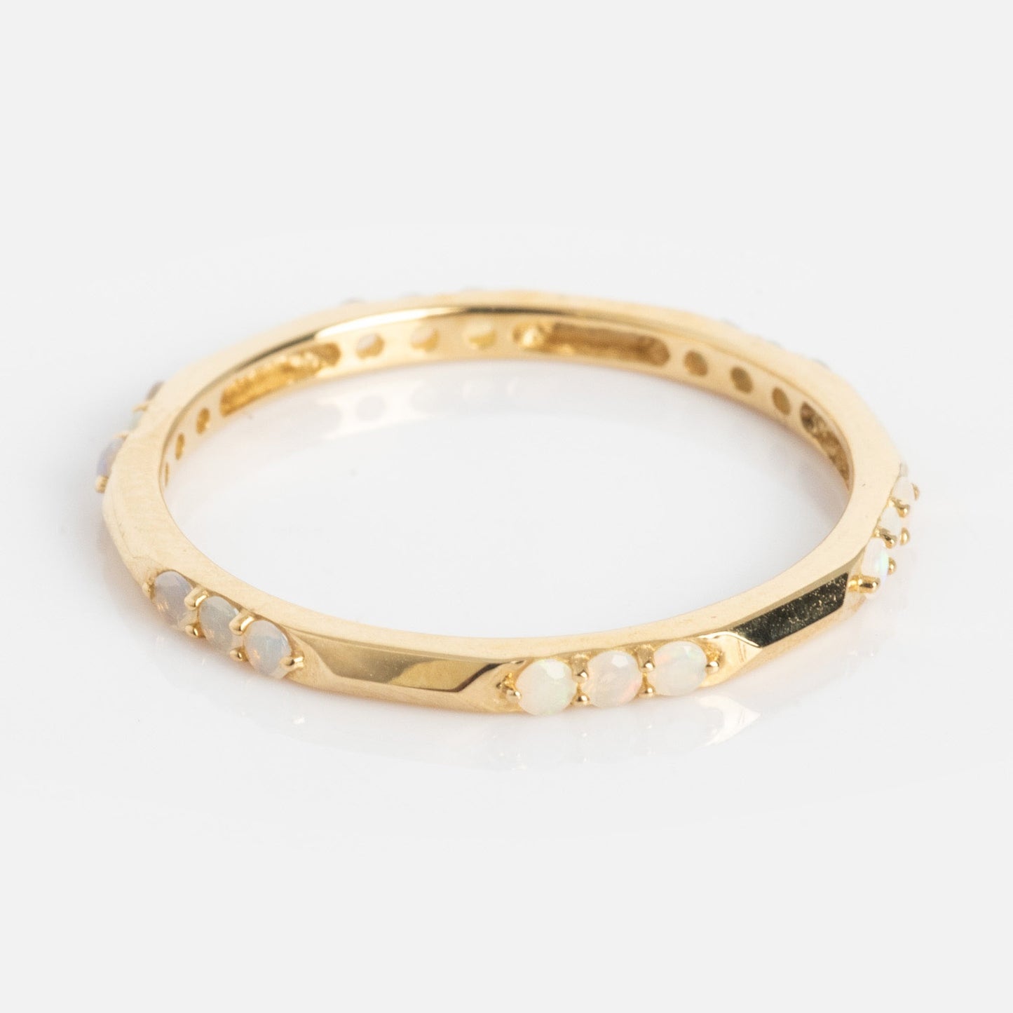 The Solid Gold Beveled Opal Stacking Ring features small round opal stones set around a thin gold band, shown against a white background.