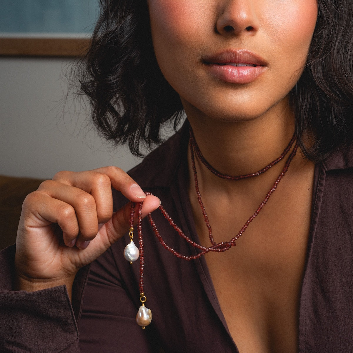 Close up of woman wearing beaded garnet tie necklace with pearls