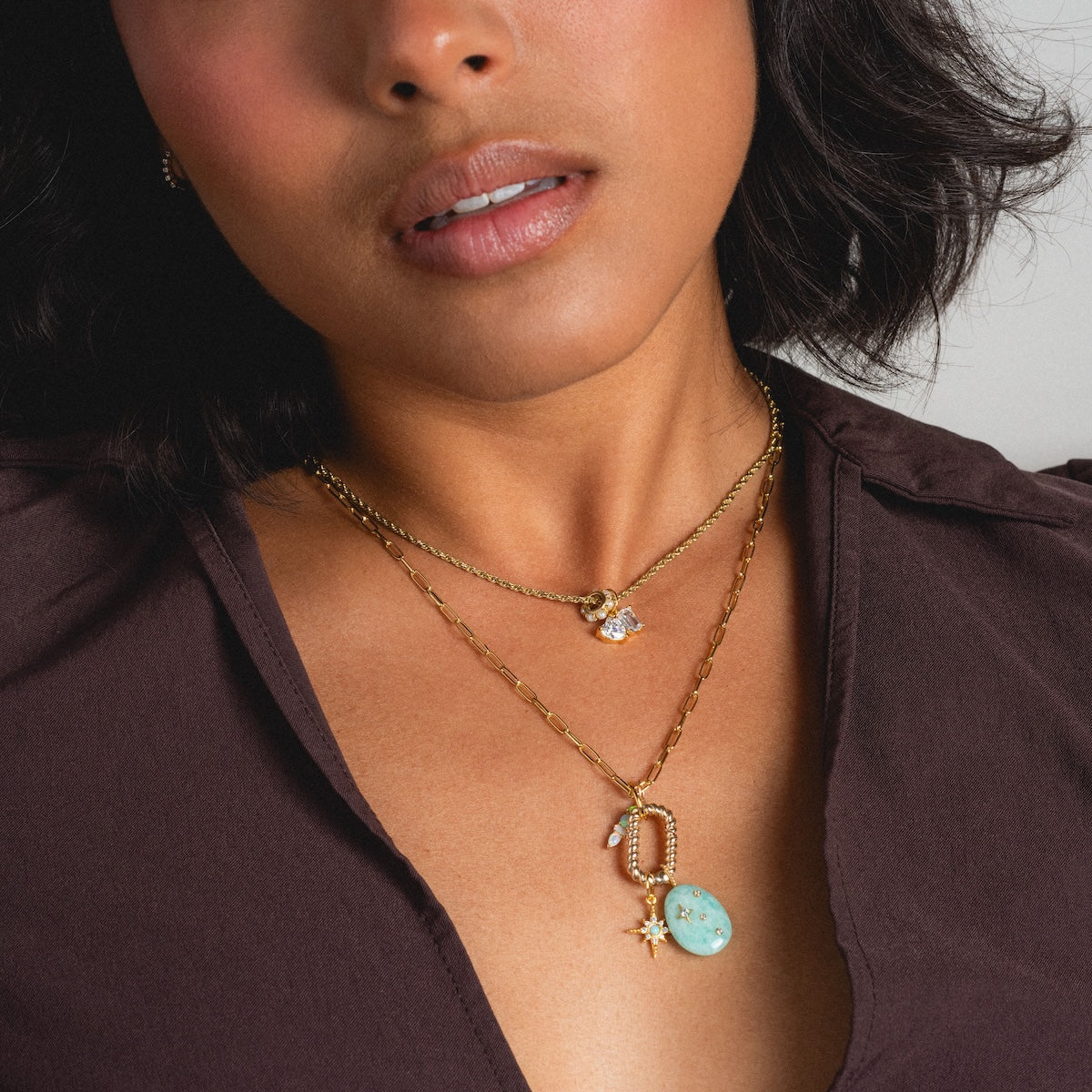 Woman wearing delicate rope and delicate paperclip chains in necklace stack with charms