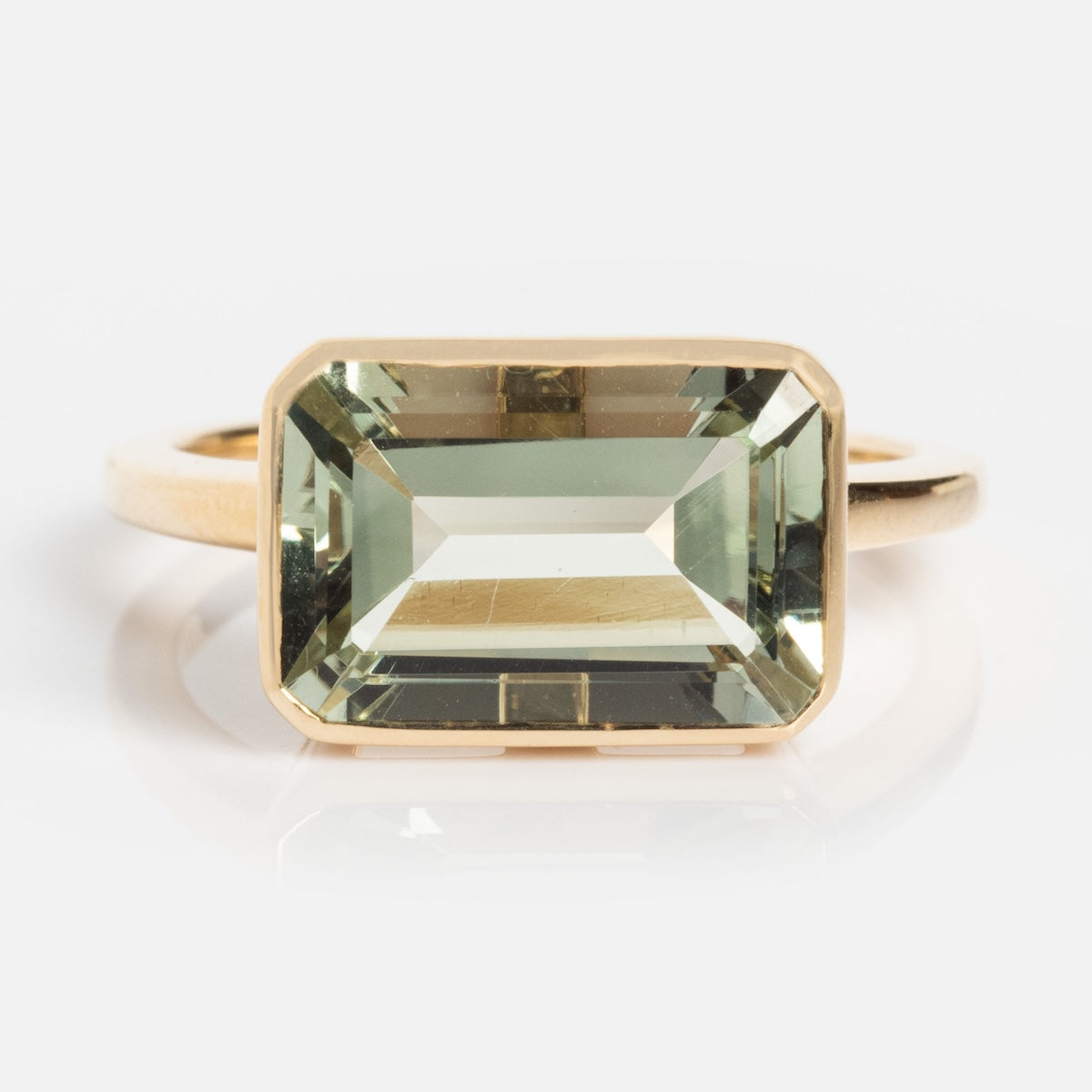The 14k Jojo Ring is crafted from solid yellow gold and showcases a large, rectangular light green natural gemstone in a simple bezel setting, all presented against a plain white background.