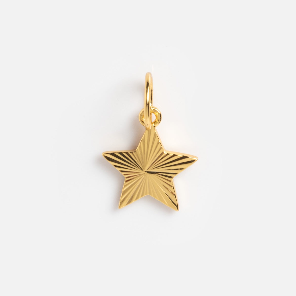 The Charms by Jurate JLA features a yellow gold plated, star-shaped pendant with engraved radiating lines and a small circular loop, shown on a plain white background.