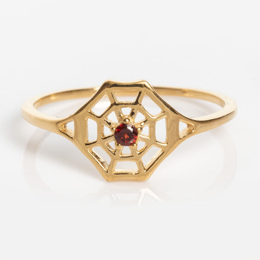 The Limited Edition Black Widow Garnet Spiderweb Ring is a delicate gold piece featuring a geometric spiderweb design with a small red garnet gemstone set at the center.