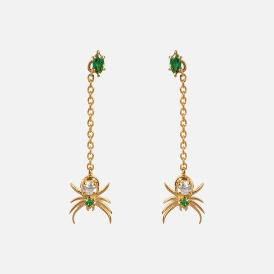 The Limited Edition Tangled Webs Spider Drop Earrings feature gold chains with dangling spider charms, each adorned with green gemstones at the stud and in the spider’s body.