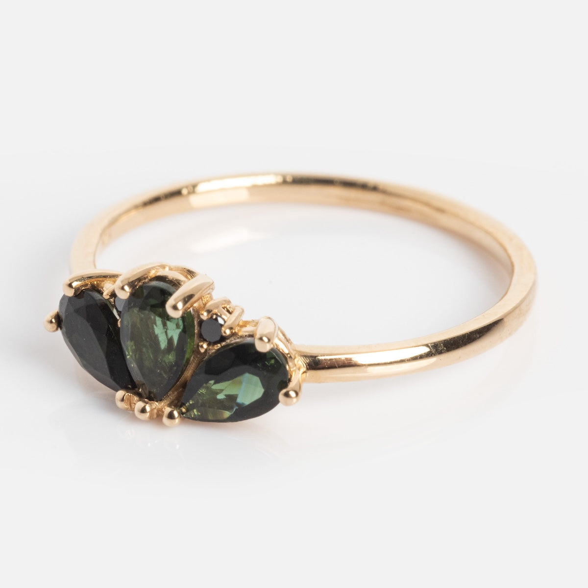 The Ava Black Diamond Ring is a 14k solid gold ring with three green pear-shaped gemstones set side by side on a simple gold band, shown against a plain white background.