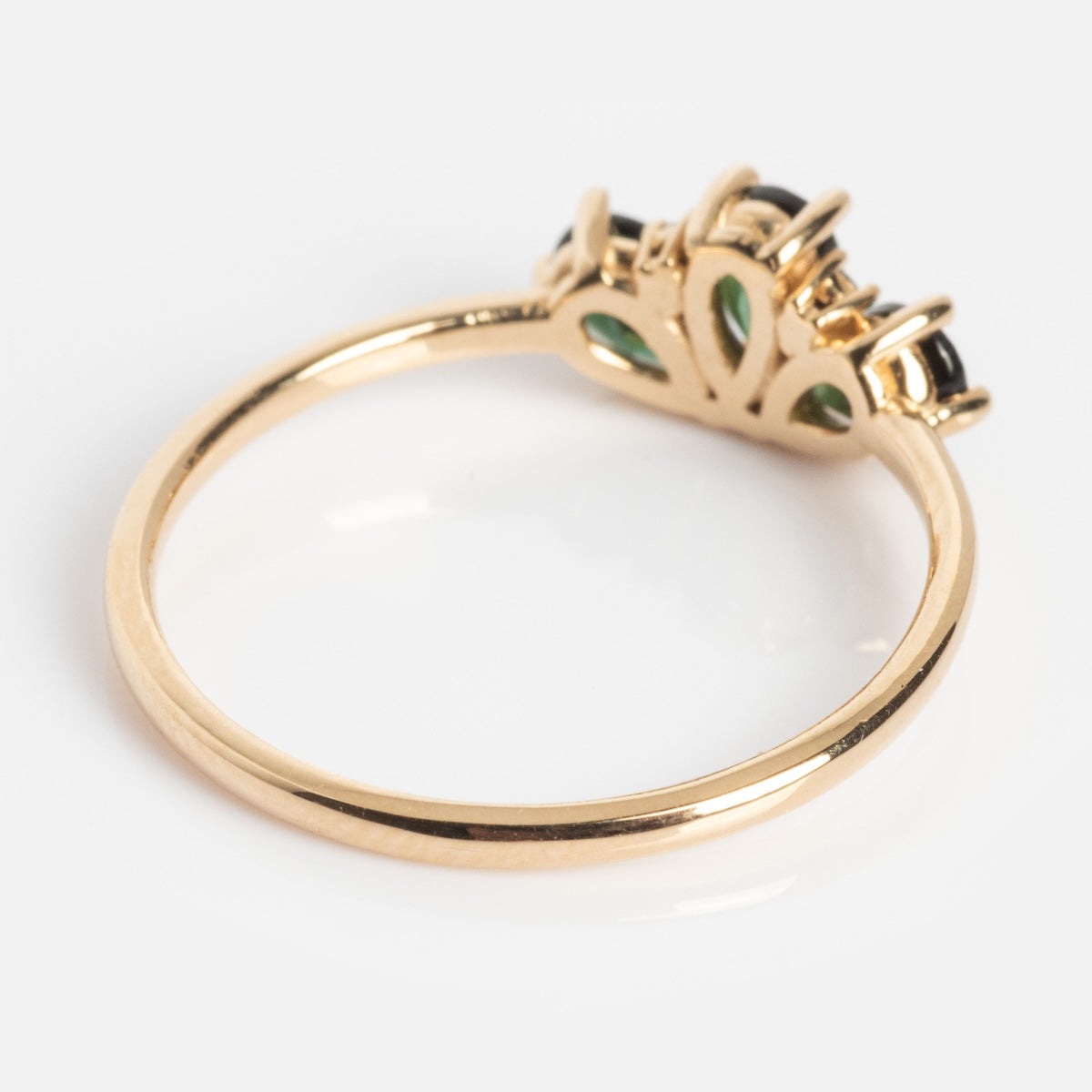 The Ava Black Diamond Ring is crafted in 14k solid gold, featuring an ornate setting with three black diamonds and green tourmaline accents on the underside, shown against a white background.