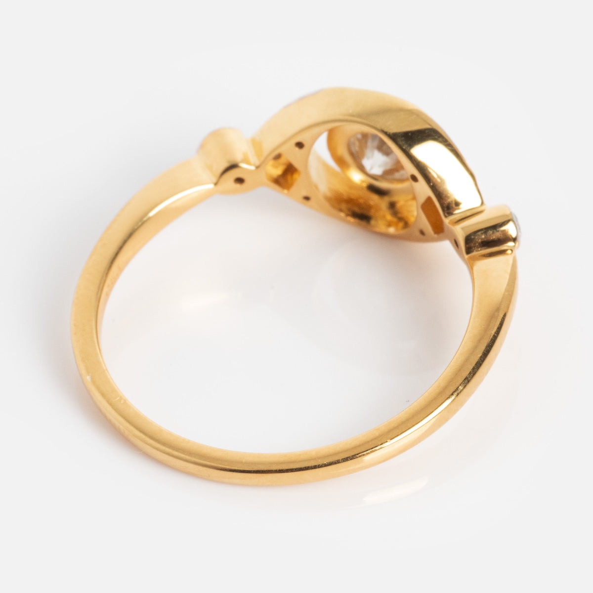 The Vienna Moissanite and Diamond Ring features a modern, sculptural gold band with a single clear gemstone, showcased on a plain white background.