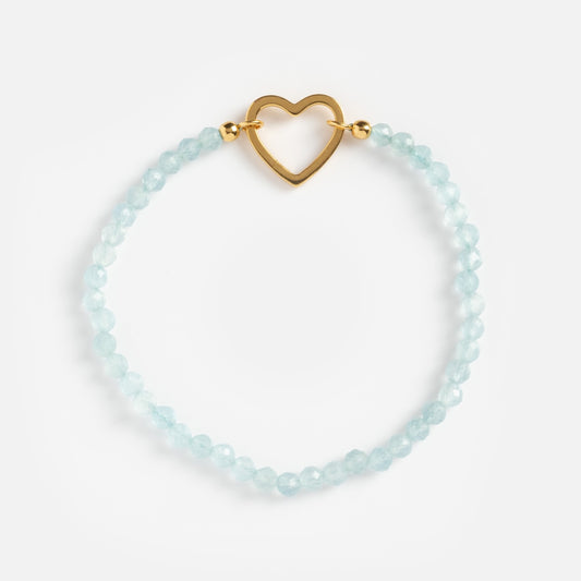 The Aquamarine Beaded Heart Clasp Bracelet showcases light blue faceted beads and a gold heart-shaped clasp, displayed on a plain white background.