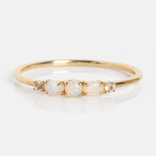 The Solid Gold 2025 October Capsule Classic Opal Trio Statement Ring features three oval opals at the center, bordered by two round diamonds on each side, showcased on a white background.