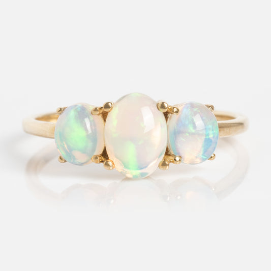 The Solid Gold 2025 October Capsule Opal Ring features three oval opals set side by side on a plain gold band, displayed against a white background. Comes with a free gift.