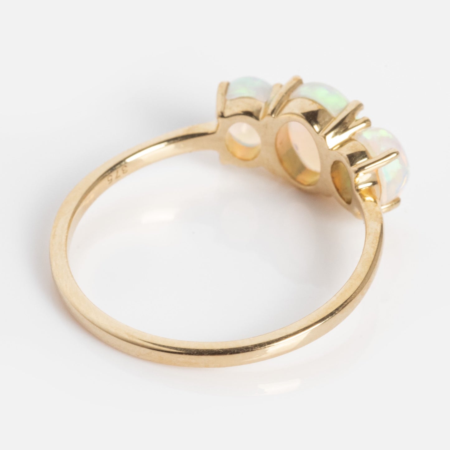The Solid Gold 2025 October Capsule Classic Opal Trio Statement Ring features a thin gold band stamped "375" and three round prong-set opals, displayed on a white background.