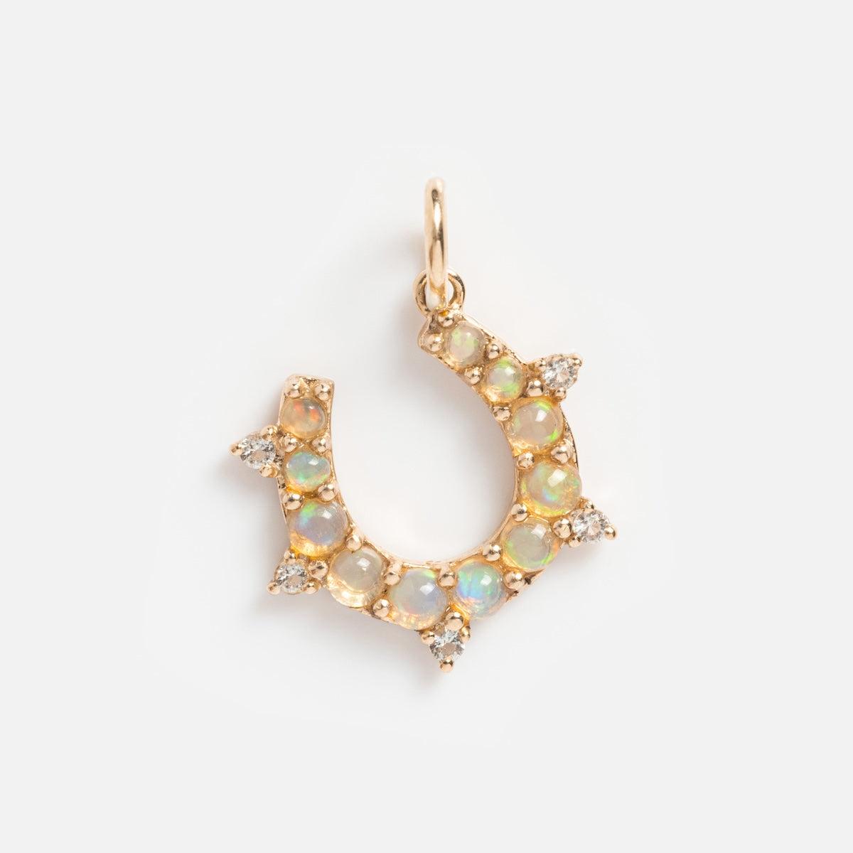 The Solid Gold Amulet Charm necklace, exclusive to Local Eclectic, features a horseshoe-shaped solid gold pendant adorned with opal gemstones and clusters of clear crystals.
