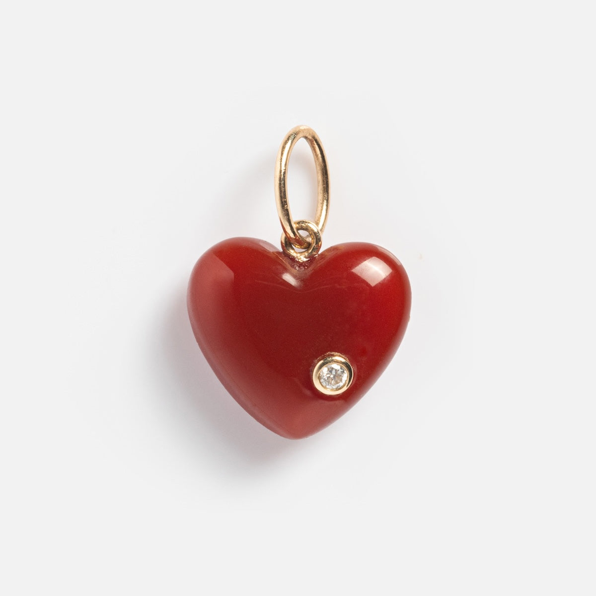 The Solid Gold Full Heart Crystal Charm features a red crystal heart with a gold loop at the top and a round diamond accent on the lower right, set against a plain white background.
