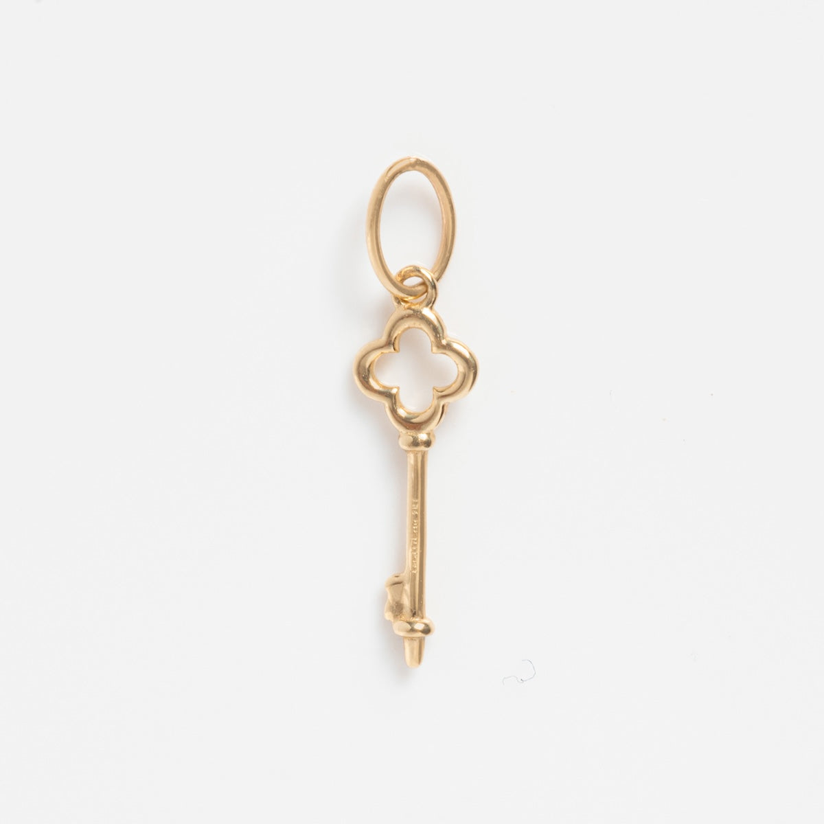 The Solid Gold Celebration Charm is a key-shaped pendant crafted in 9k yellow gold with a clover-shaped bow and round top loop, shown against a plain white background.