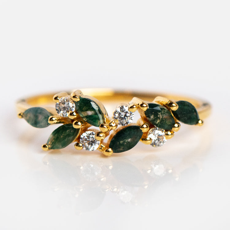 The Gemstone Orchard Ring is a gold band set with marquise moss agate and round white diamonds in a clustered, nature-inspired design, photographed on a white background.