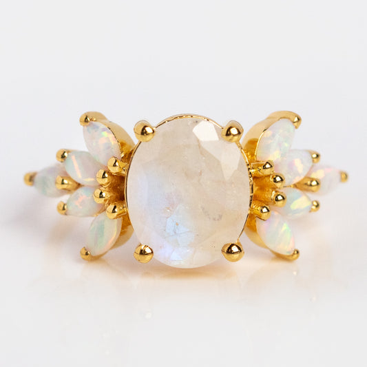 The Rainbow Moonstone and Opal Candy Crush Ring showcases a large oval rainbow moonstone accented by clusters of marquise-cut opals on each side, set in 14k gold vermeil, with a floral-inspired design.