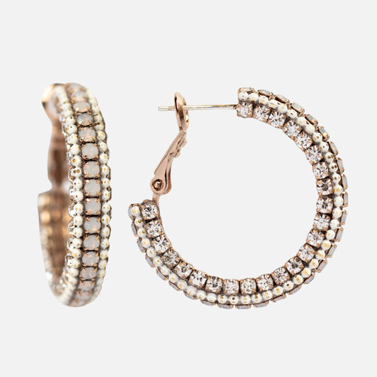 The Astaire Hoop Earrings are gold hoops encrusted with rows of sparkling clear crystals, displayed on a white background—one earring open to reveal the clasp, and the other closed.