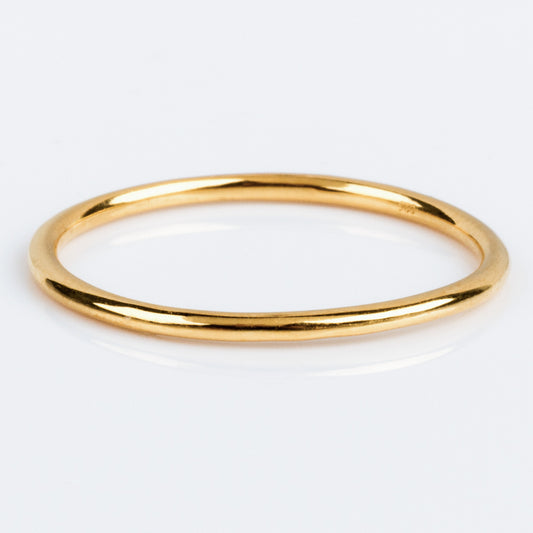 Twiggys Simple Band is a sleek, thin 18K yellow gold ring with a smooth, polished finish, shown against a white background.