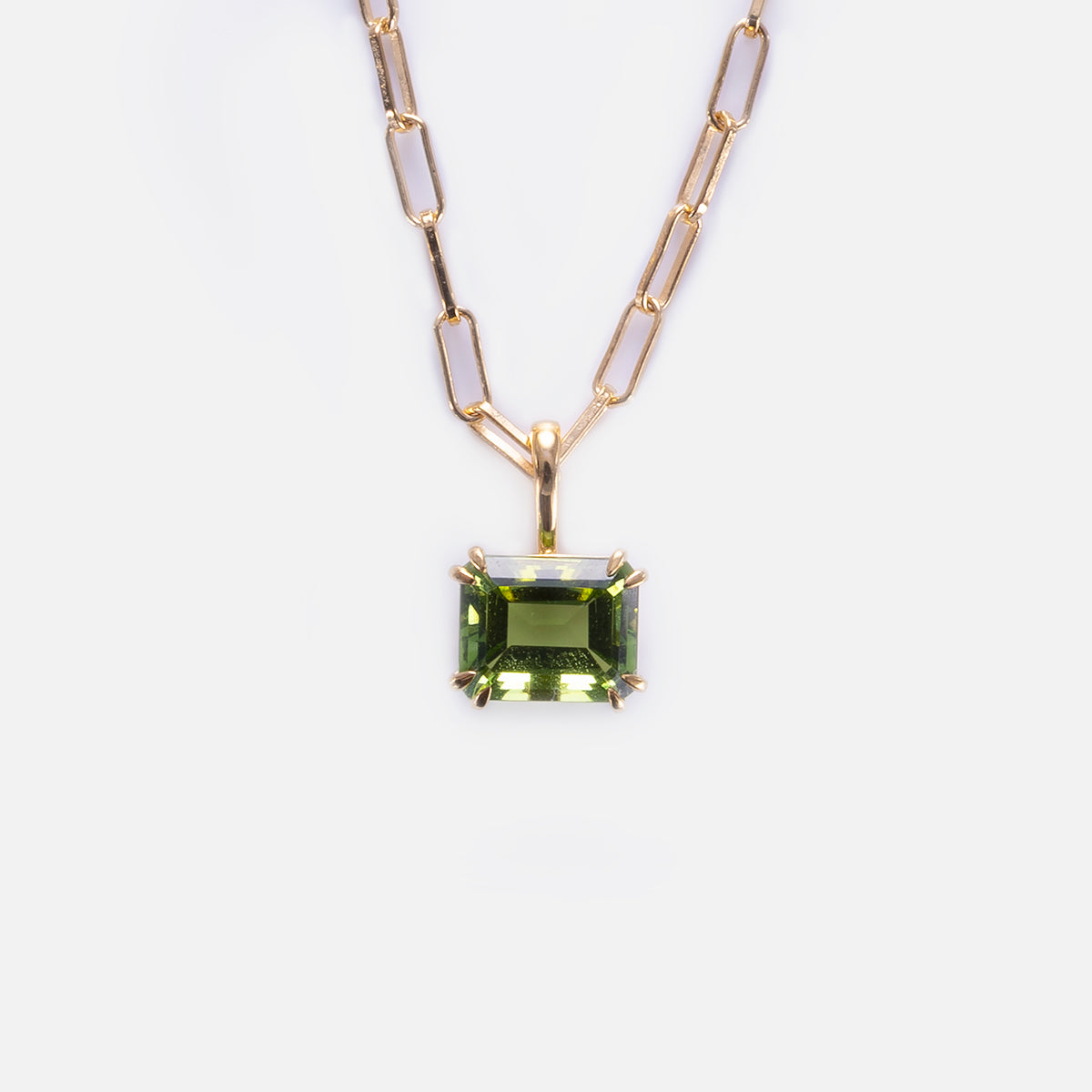 The Born to Shine Birthstone Necklace features a gold paperclip chain with elongated links and a rectangular green gemstone pendant in a prong setting, shown on a white background—ideal as a unique birthstone gift.