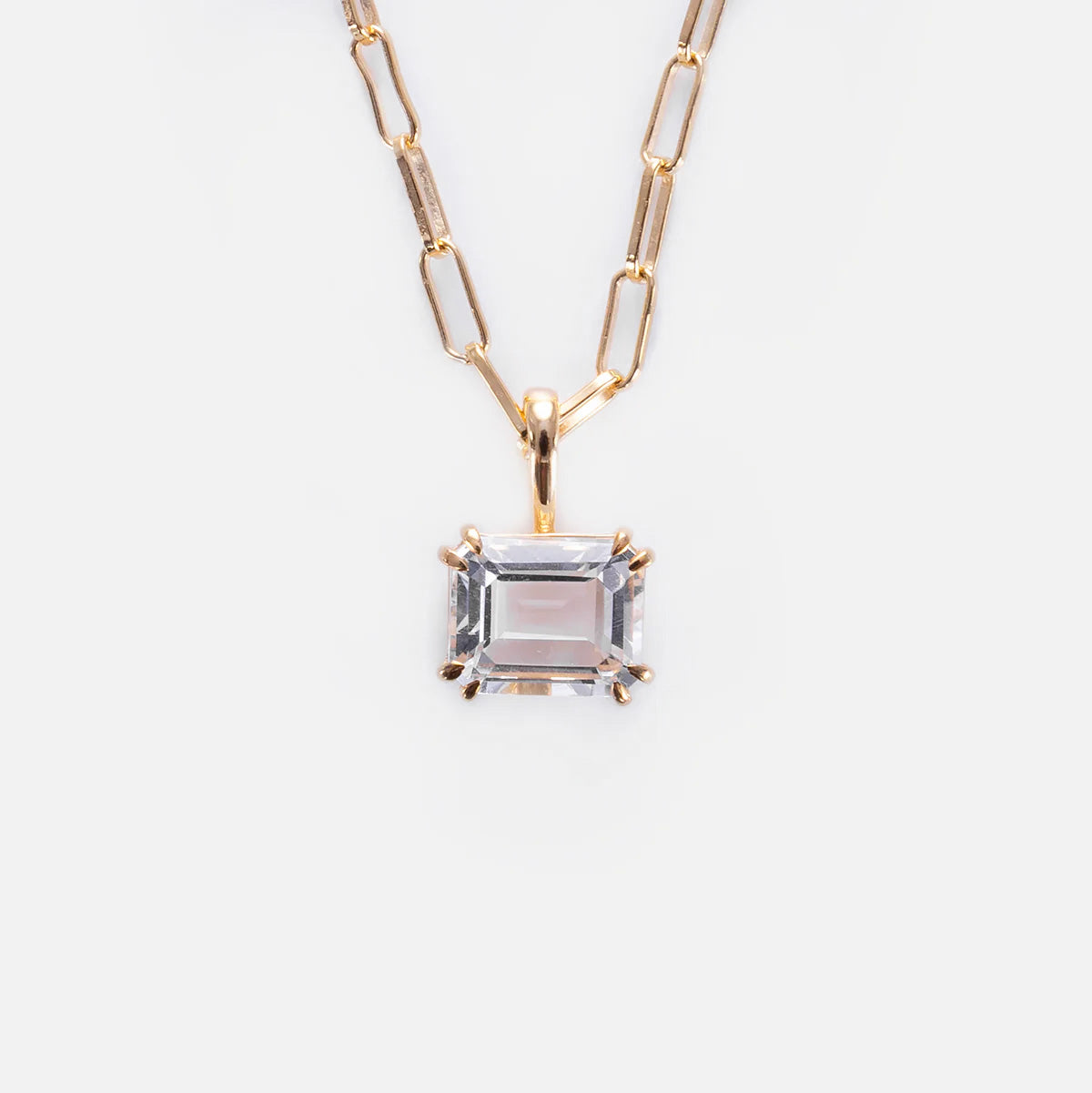 The Born to Shine Birthstone Necklace features a gold paperclip chain with a rectangular, emerald-cut clear gemstone pendant in a gold prong setting, shown against a white background.