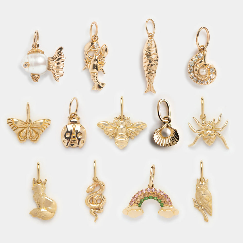 The Solid Gold Nature Charm set features twelve small animal charms, shaped like creatures and objects—fish to fox—arranged in three neat rows on a light background, ideal for fans of unique spiritual jewelry.