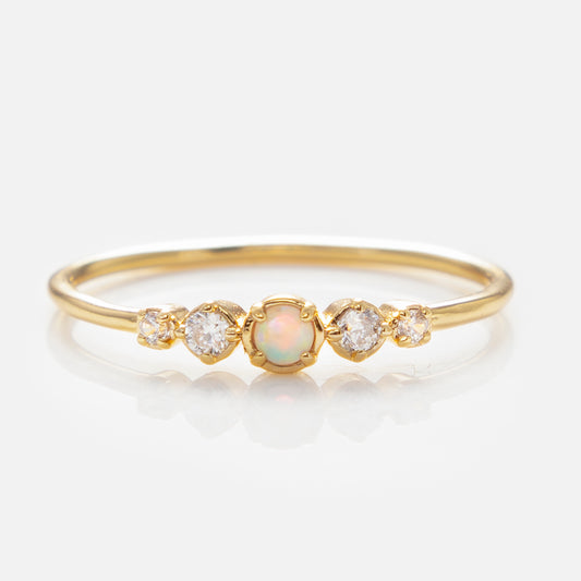 The Opal Stacking Ring is a delicate 14k gold-plated band featuring a central opal gemstone and two small round diamonds, perfect for stacking or wearing solo against a plain white background.