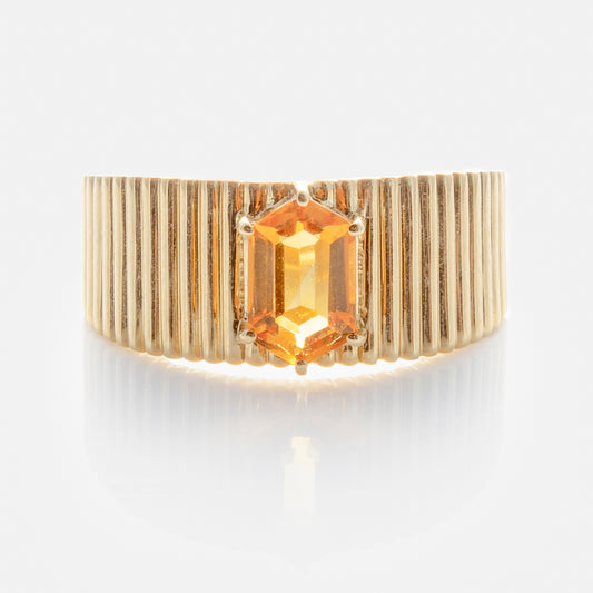 The Solid Gold Citrine Bold Fluted Cigar Band is a 9k yellow gold ring with vertical grooves and a rectangular, faceted orange citrine gemstone set at the center.