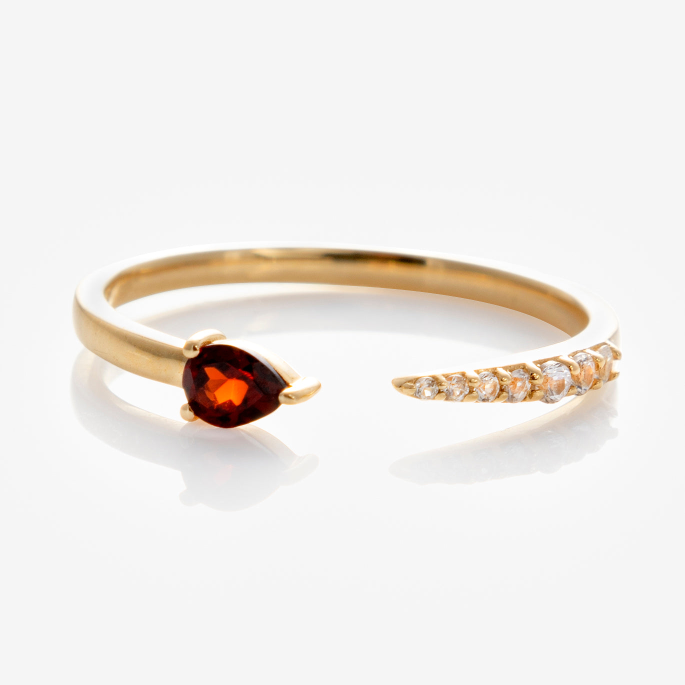 The Solid Gold Garnet and Sapphire Open Front Band in 9k yellow gold features a pear-shaped garnet on one end and a row of white sapphires on the other, shown against a white background.